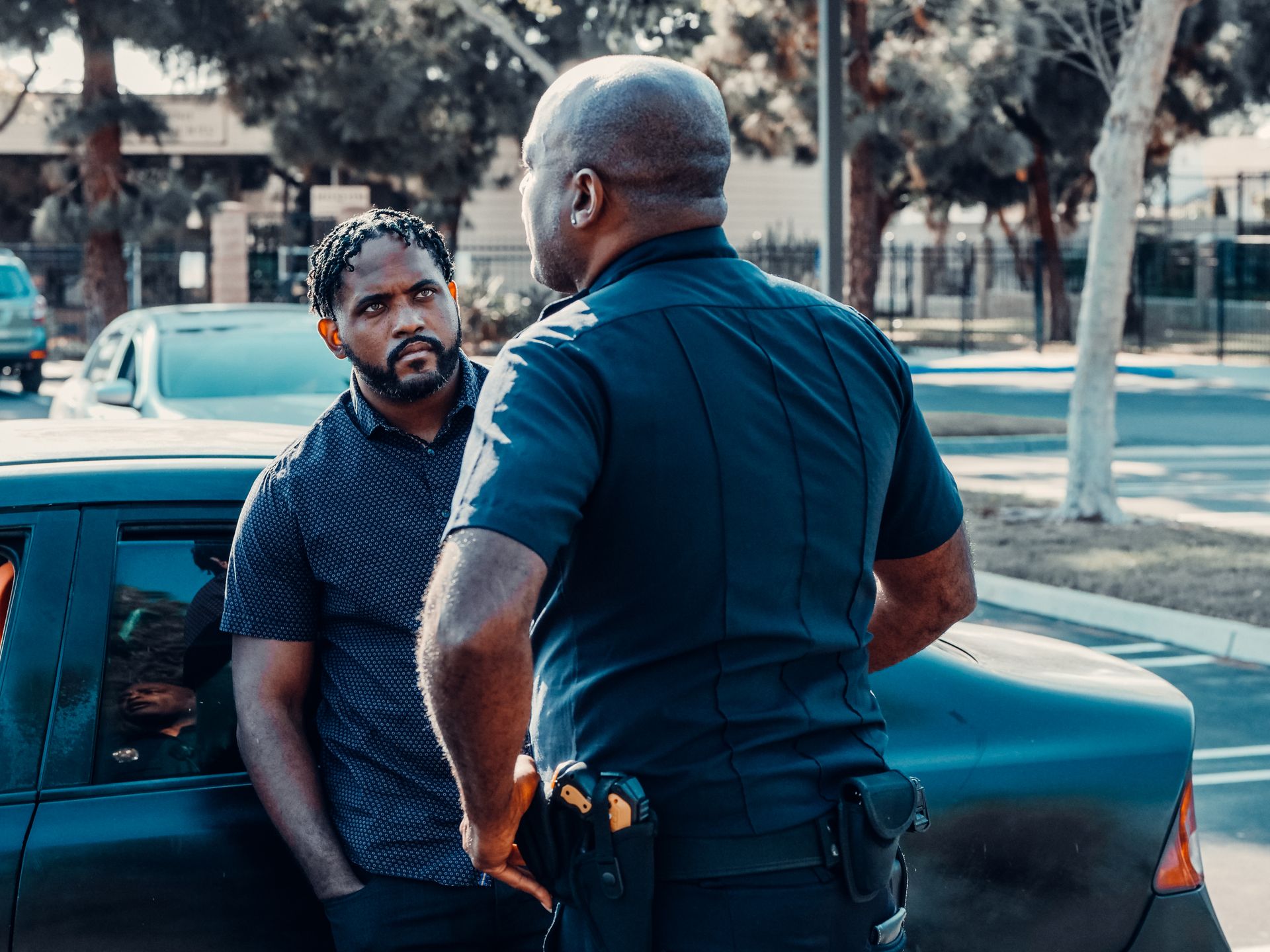 Braided Hair Man Standing near the Car Looking at the Policeman
