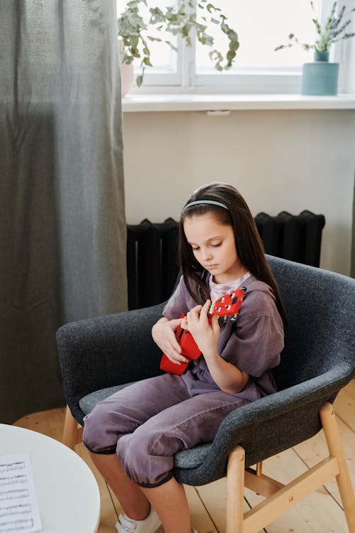 Free Photo of a Cute Girl Playing a Red Ukulele  Stock Photo