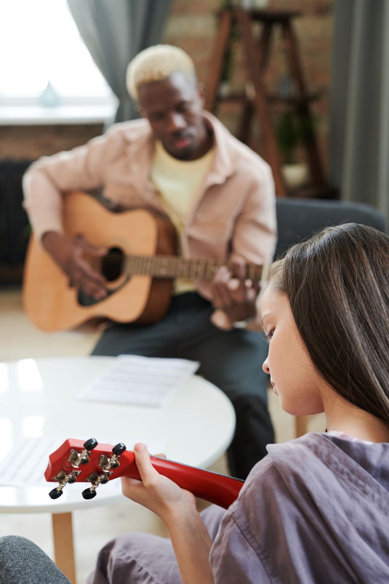 Young girl learning guitar with an instructor in cozy room.
