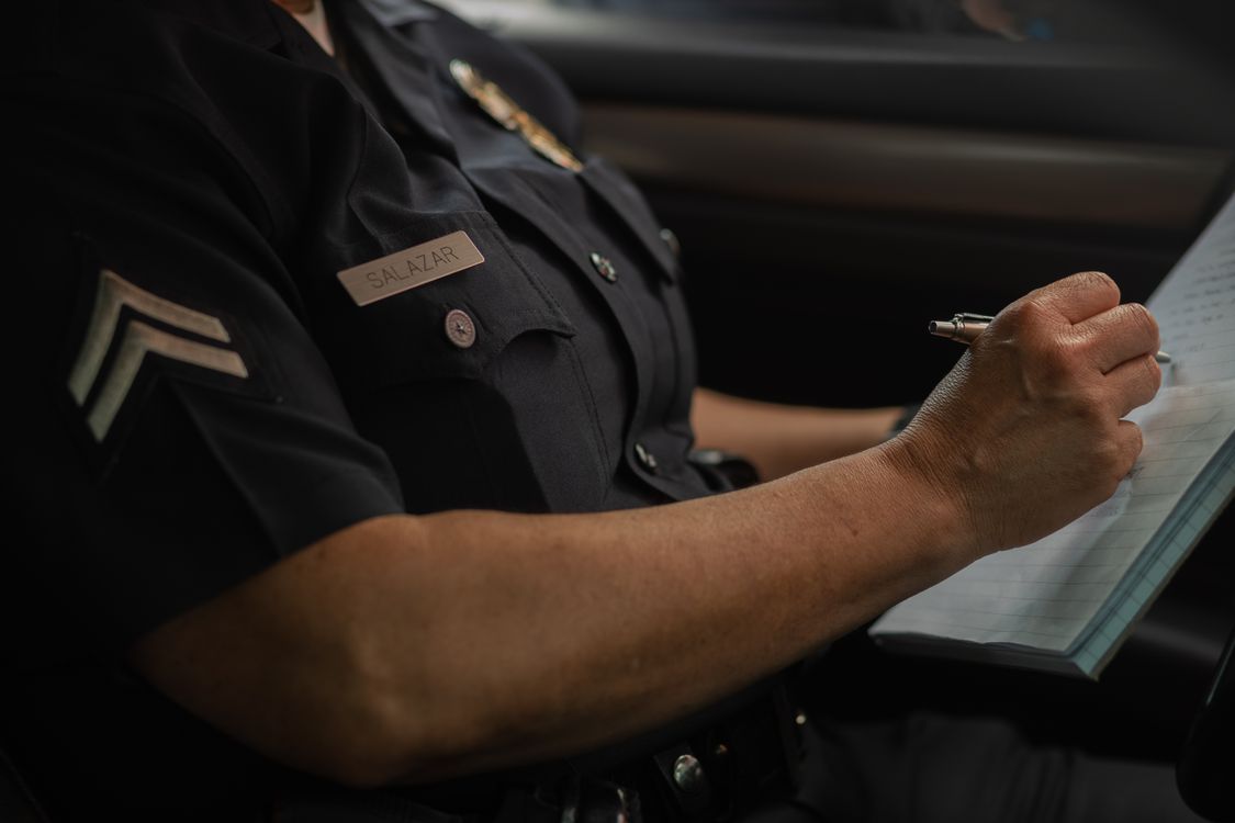 Person Wearing Police Uniform Writing on a Notebook · Free Stock Photo