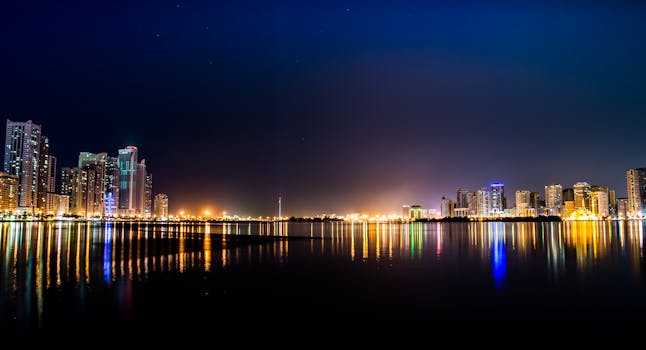 Stunning night view of a city skyline reflecting on calm waters, showcasing city lights.