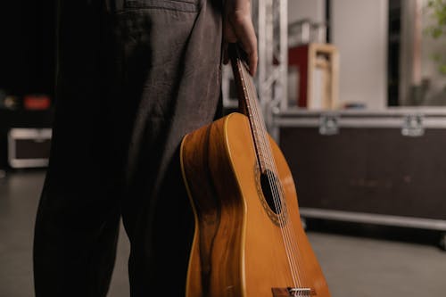 Person Holding a Brown Acoustic Guitar 