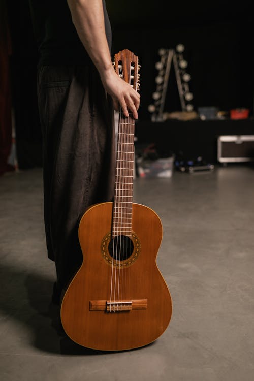 A Person Standing Holding Brown Acoustic Guitar