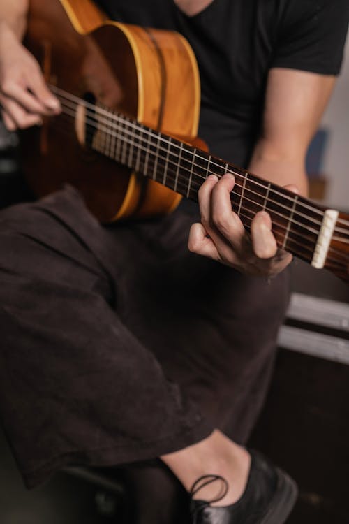 Kostenloses Stock Foto zu akustische gitarre, gekreuzten beinen, gitarre spielen