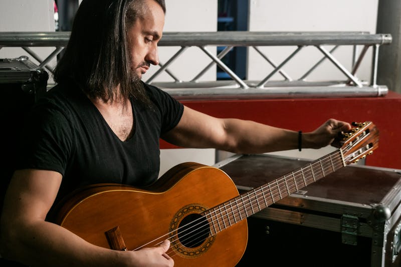 Musician tuning a guitar backstage before a performance