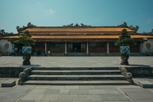 Free Beautiful temple courtyard featuring traditional architecture and potted plants under a clear sky. Stock Photo