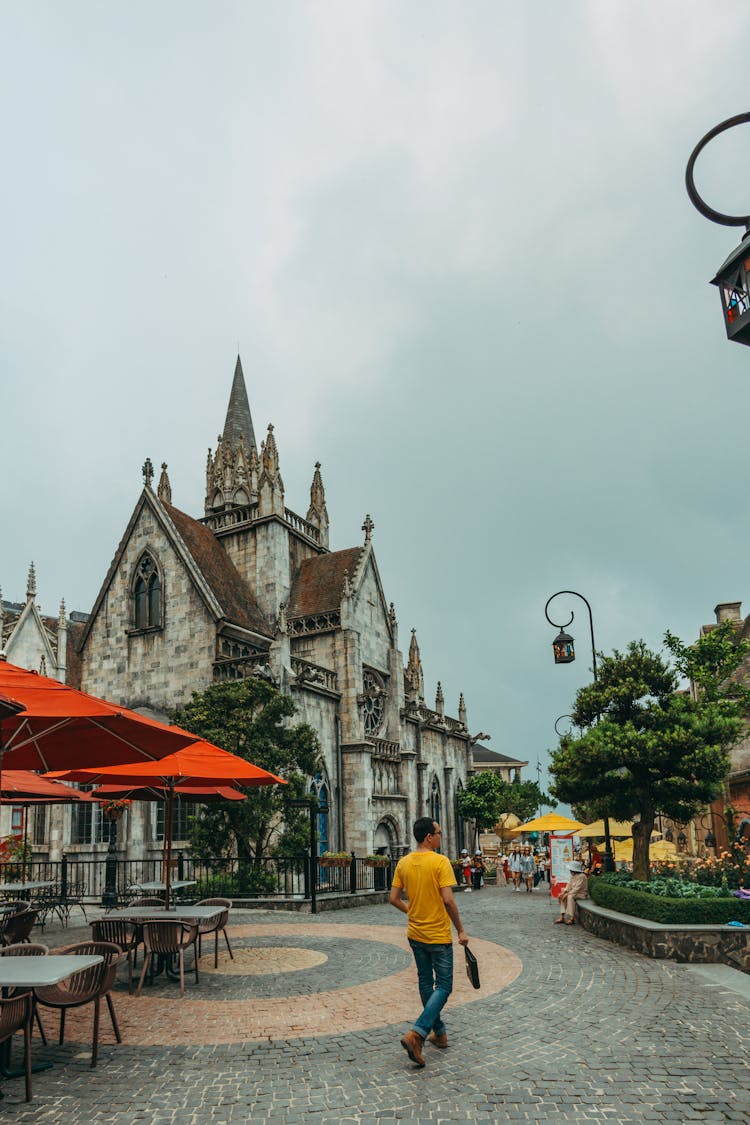 Man In Yellow Shirt Walking In The Plaza Near A Cathedral