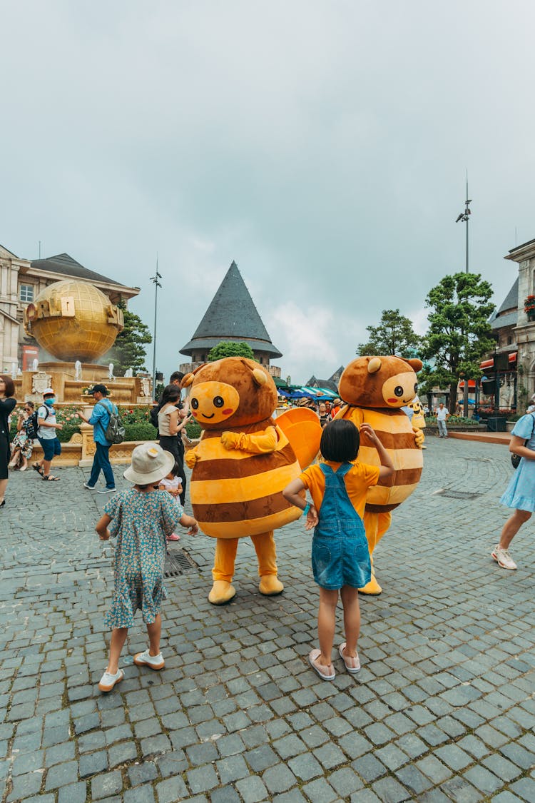 Kids Standing In Front Of Bee Mascots 