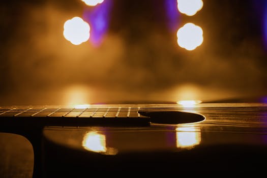 Close-up view of an acoustic guitar in warm, dramatic lighting with light reflections.