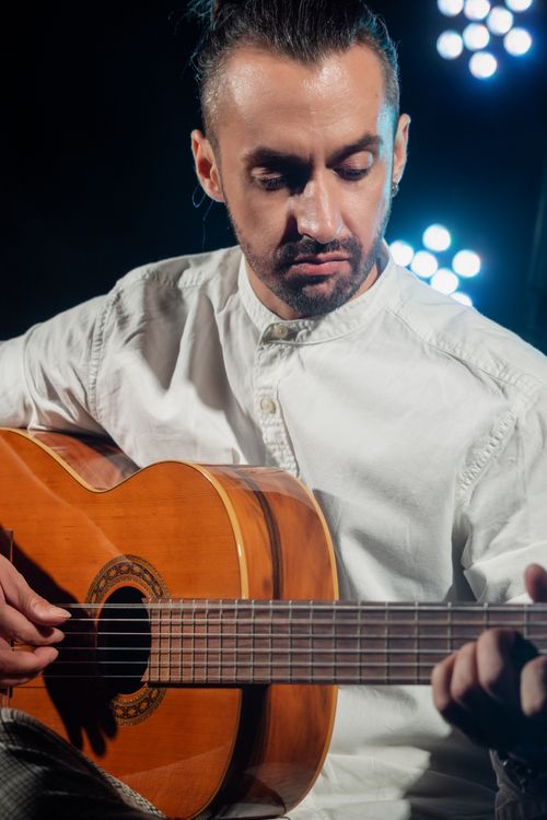 Free Bearded musician performs passionately with an acoustic guitar on stage. Stock Photo