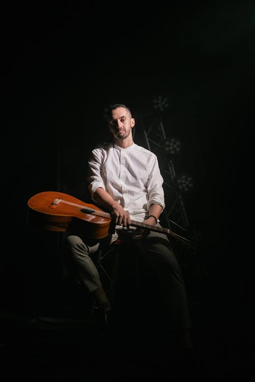 Man in White Long Sleeves Sitting with a Guitar