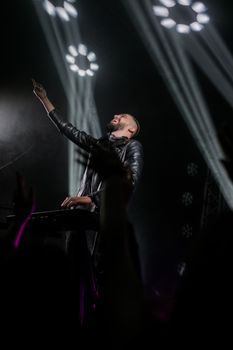 A passionate musician performs on stage, engaging with the audience under vibrant lights.