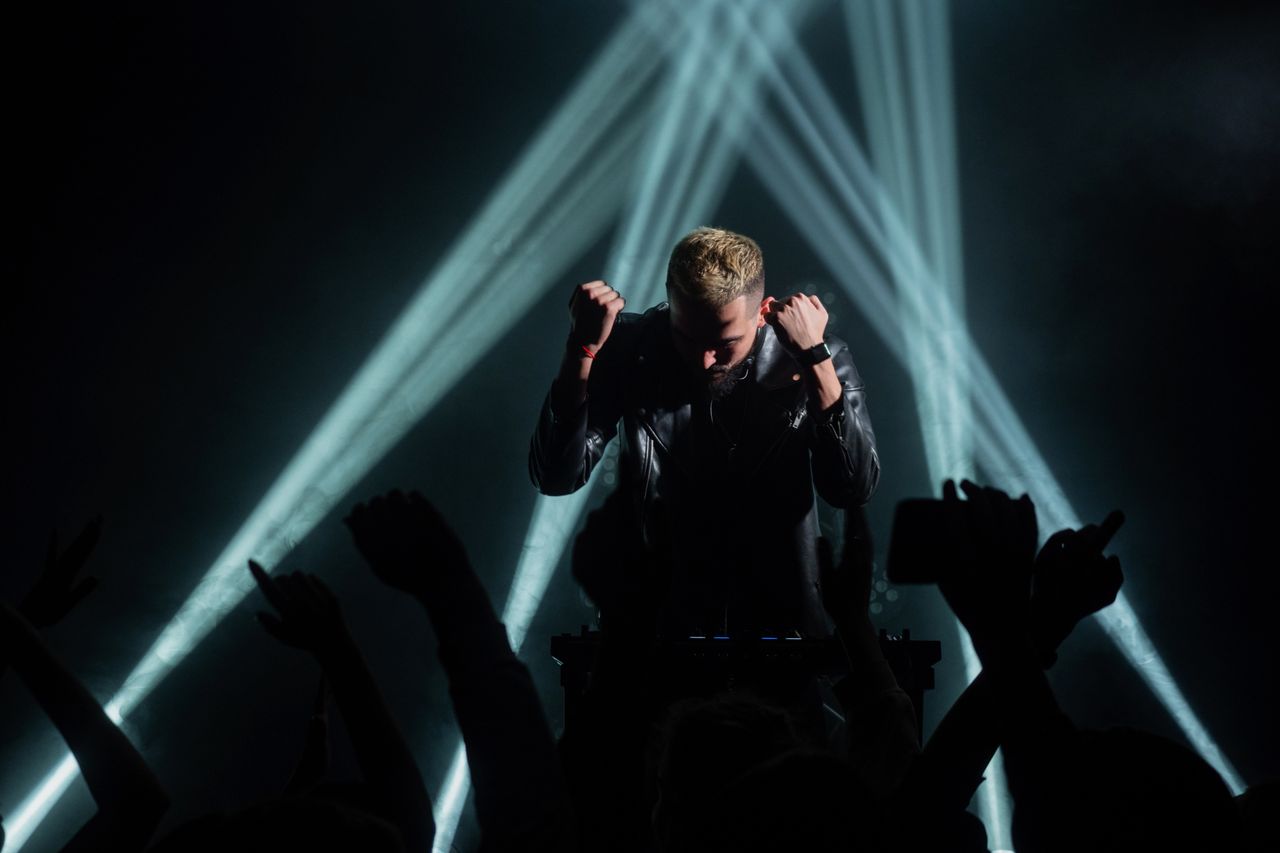energetic dj performing on stage with dramatic lighting and crowd inte