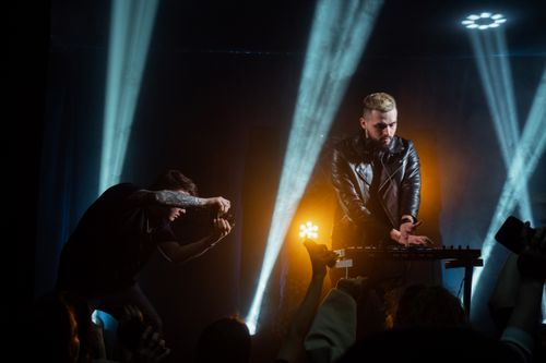 Free DJ performing live music set under colorful lights during a thrilling night concert. Stock Photo