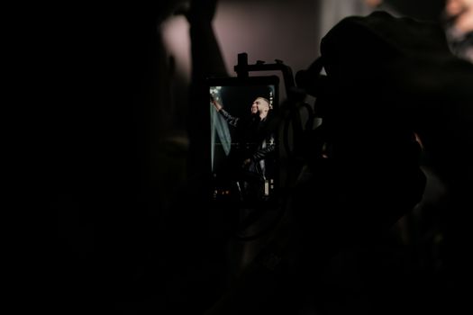 A performer on stage captured through a smartphone at a dark, energetic concert.