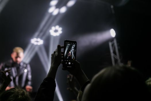 A smartphone captures a live concert moment with an illuminated stage.