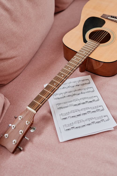 Wooden Acoustic Guitar Laid on a Sofa