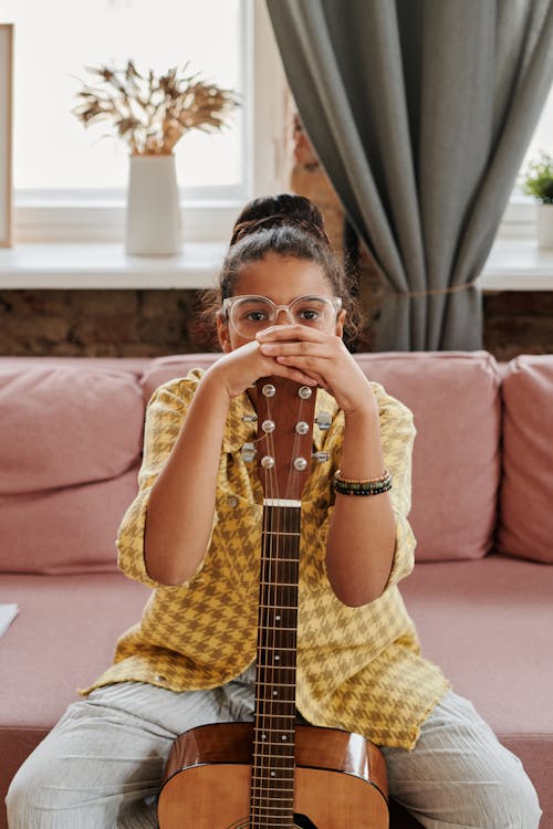 Photo of a Girl Wearing Clear Eyeglasses Holding an Acoustic Guitar