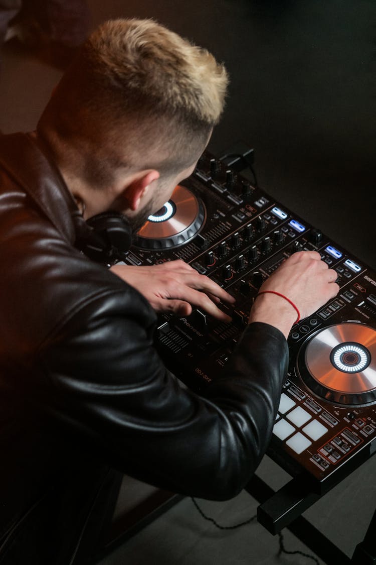 Man Wearing Black Leather Jacket Using A DJ Mixer