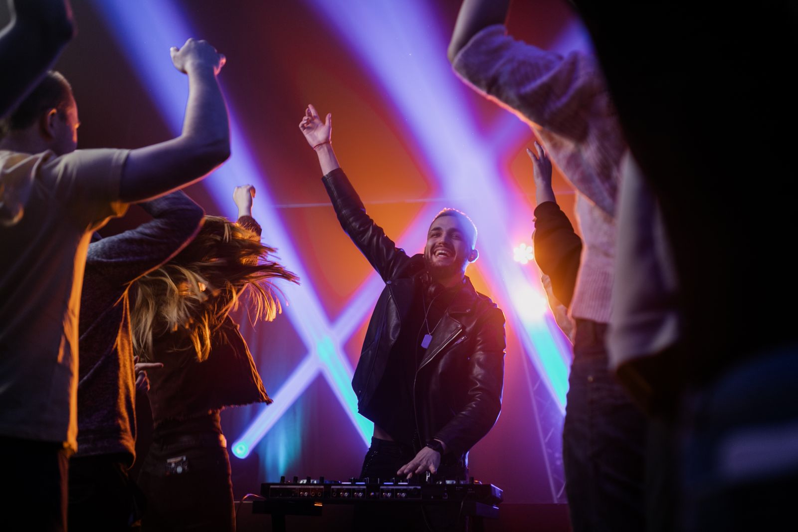 DJ performing at a lively party venue with colourful lights and a dancing crowd