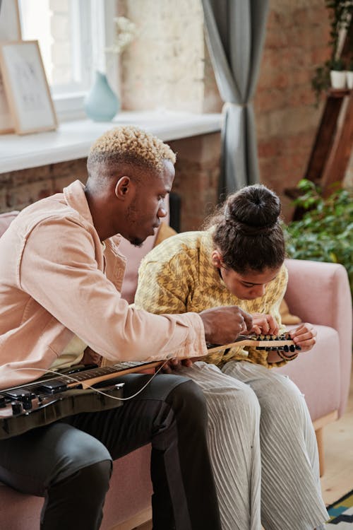 A Man and a Girl Putting on Strings on a Guitar