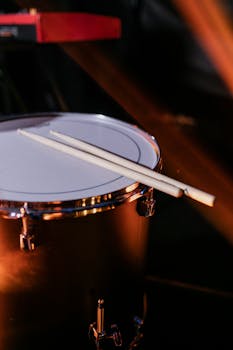 Close-up view of a drum with drumsticks placed on it, highlighting musical performance.