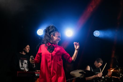 Female singer performs live with band under bright stage lights.