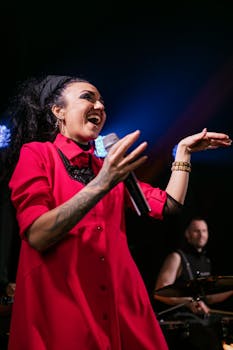 Energetic singer in a vibrant pink dress performing live on stage.