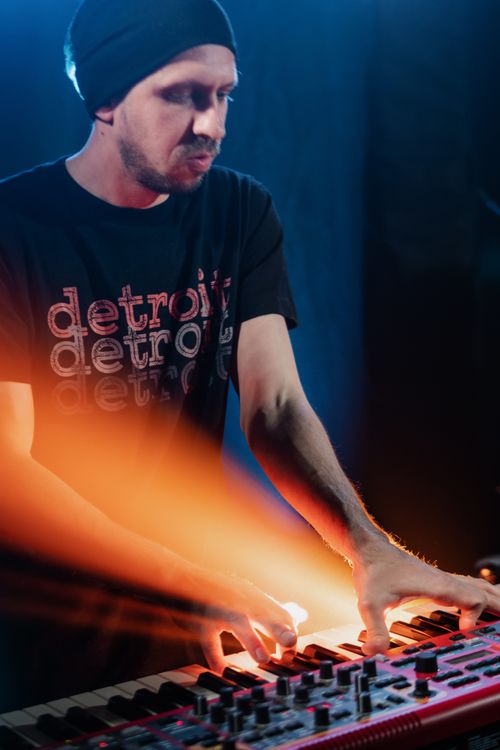 Free Man playing electronic keyboard under spotlight, creating vivid music experience. Stock Photo