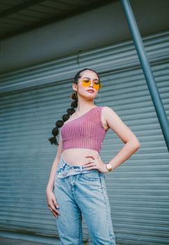 Confident woman with braided hair and sunglasses posing stylishly in Davao's urban environment.