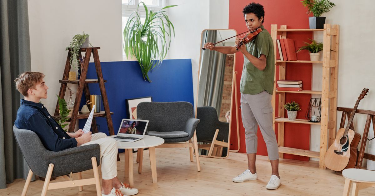 Young musicians collaborating in a circle with instruments and laptops