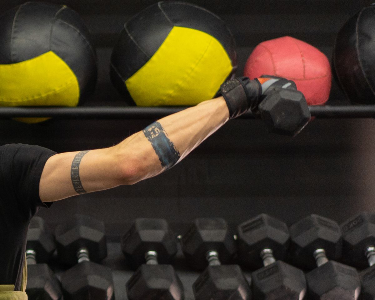 Gym gloves and wrist support on a lifter next to dumbbells