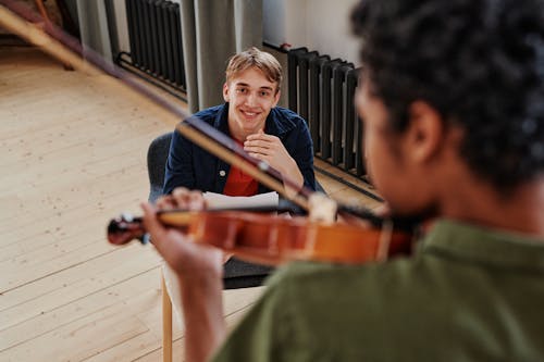 Free Man Smiling While Watching the Person Playing Violin  Stock Photo