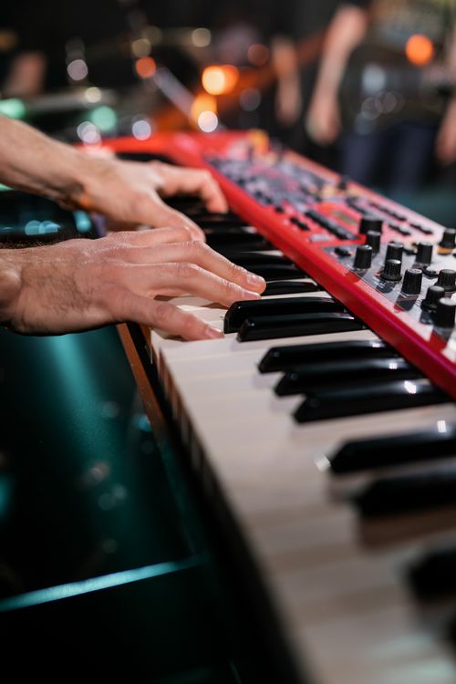 Free Musician playing a red keyboard live on stage, creating an engaging musical performance. Stock Photo