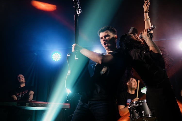 Man And Woman Standing Back To Back While Performing On Stage 