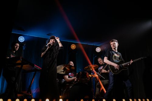Free Live band performance with singer on stage under colorful lights. Stock Photo