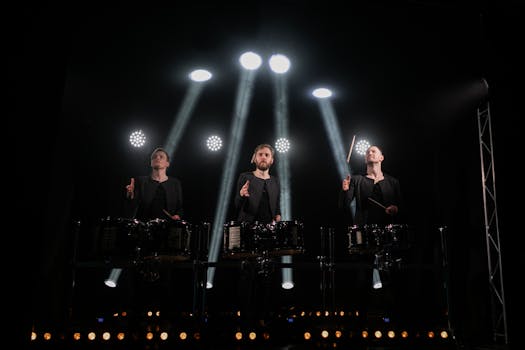 Three drummers performing under bright stage lights, creating an intense musical experience.