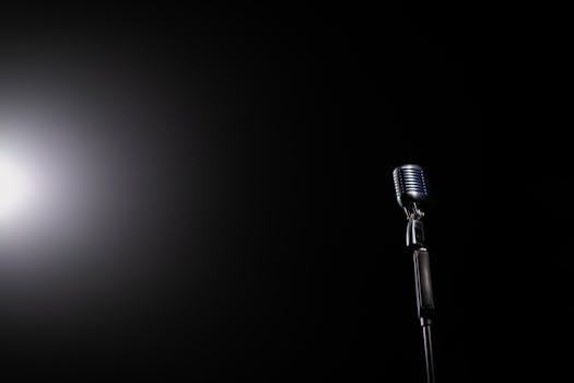 A vintage microphone illuminated by a spotlight against a dark background, perfect for music-related themes.