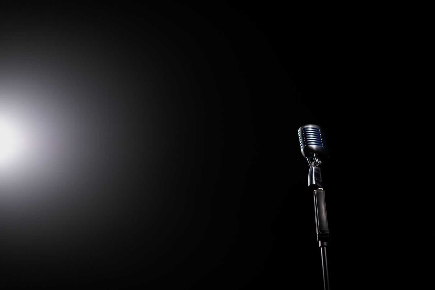A silver vintage microphone under a spotlight.