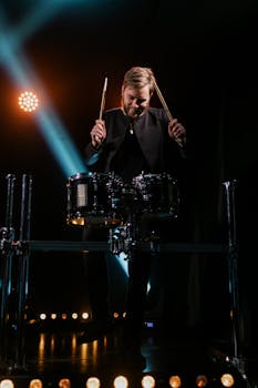 Energetic drummer performing live on stage with vibrant lighting effects.