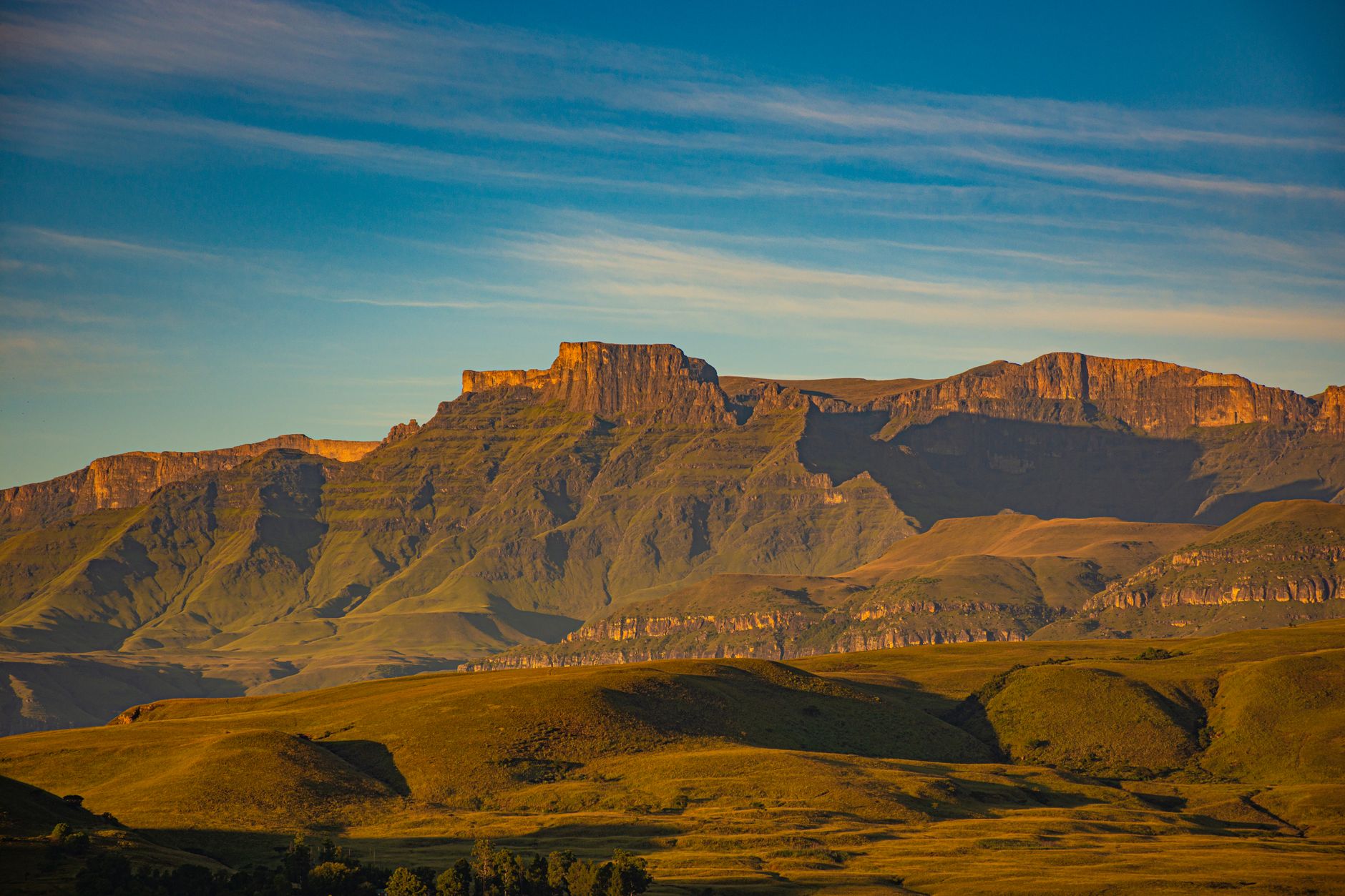 Stunning view of Drakensberg Mountains in South Africa during sunset, showcasing rugged terrain and vibrant colors.