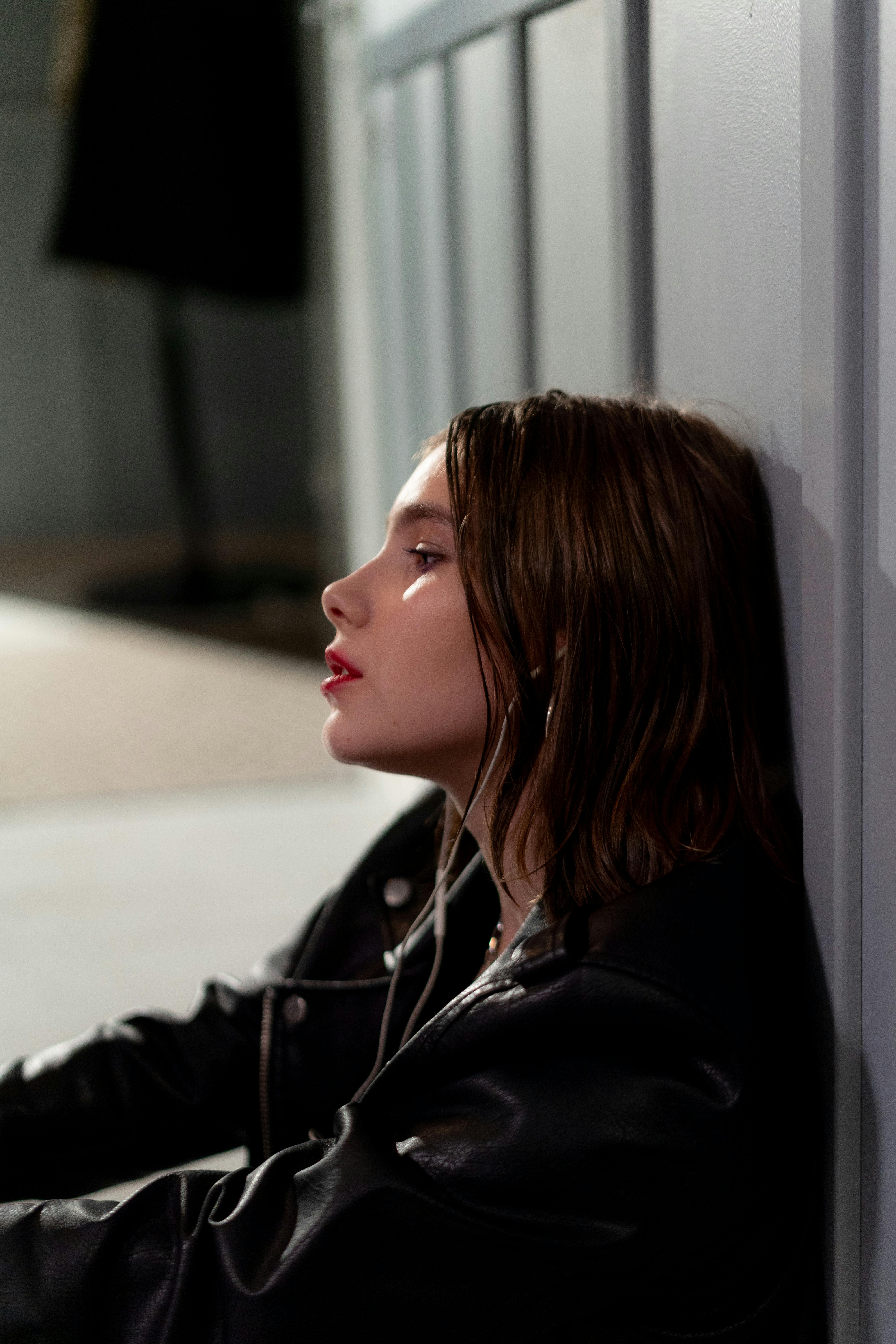Stylish young woman in a black leather jacket listening to music indoors.