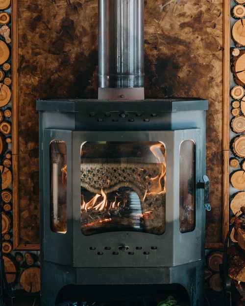 Free Orange flame of vintage metal burning fireplace placed near wooden wall in cozy house Stock Photo