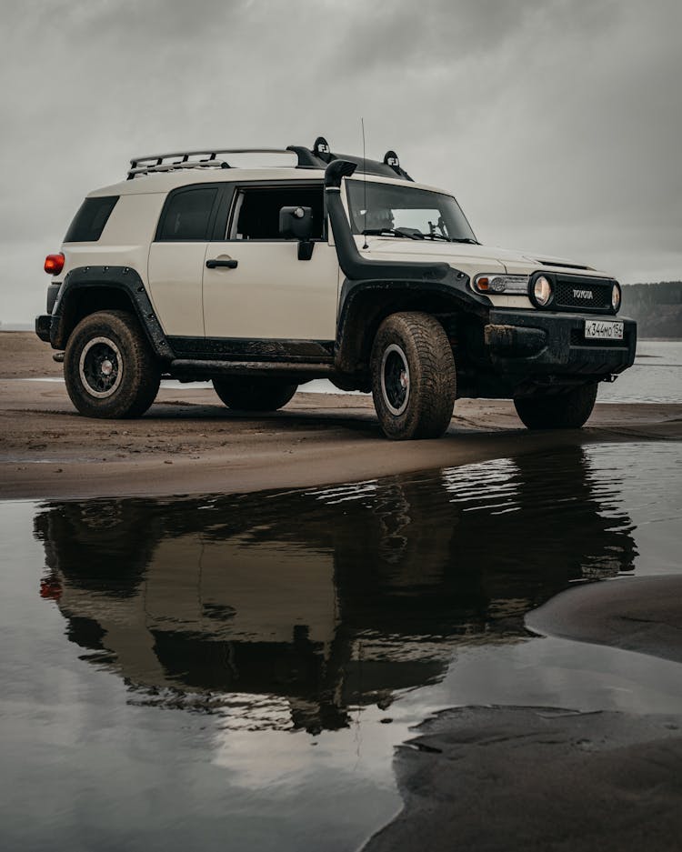 SUV Car Parked Near Lake On Cloudy Day