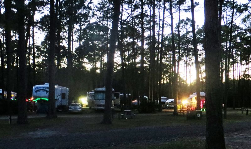 Rodina sedí na kempingových židlích u campervanu na dovolené