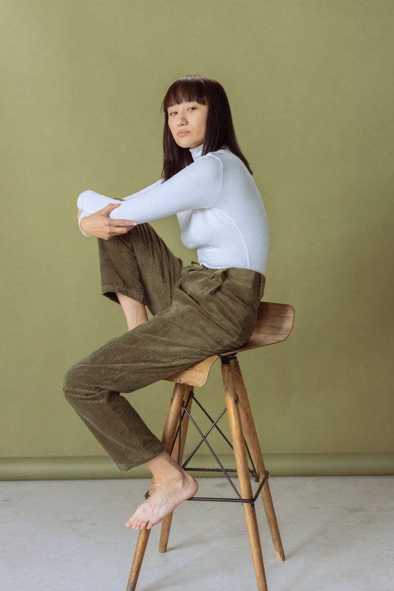 woman in brown corduroy trousers and cream turtleneck