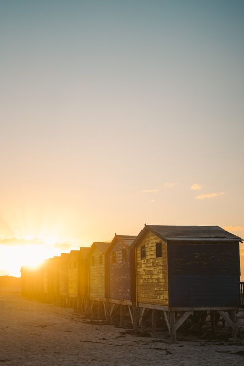 Free Breathtaking sunset view over wooden beach huts in Cape Peninsula, capturing nature's golden hour glow. Stock Photo