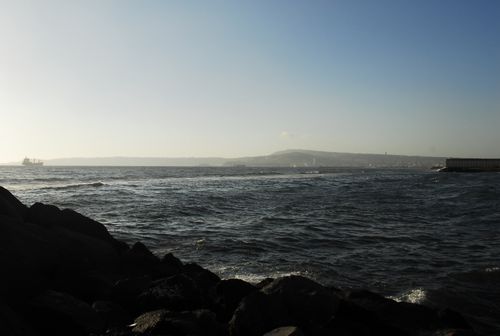 Free Peaceful coastal view with rocky shore and distant ship under a clear sky. Stock Photo