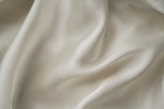 Close-up of smooth white silk fabric with soft folds and gentle draping.