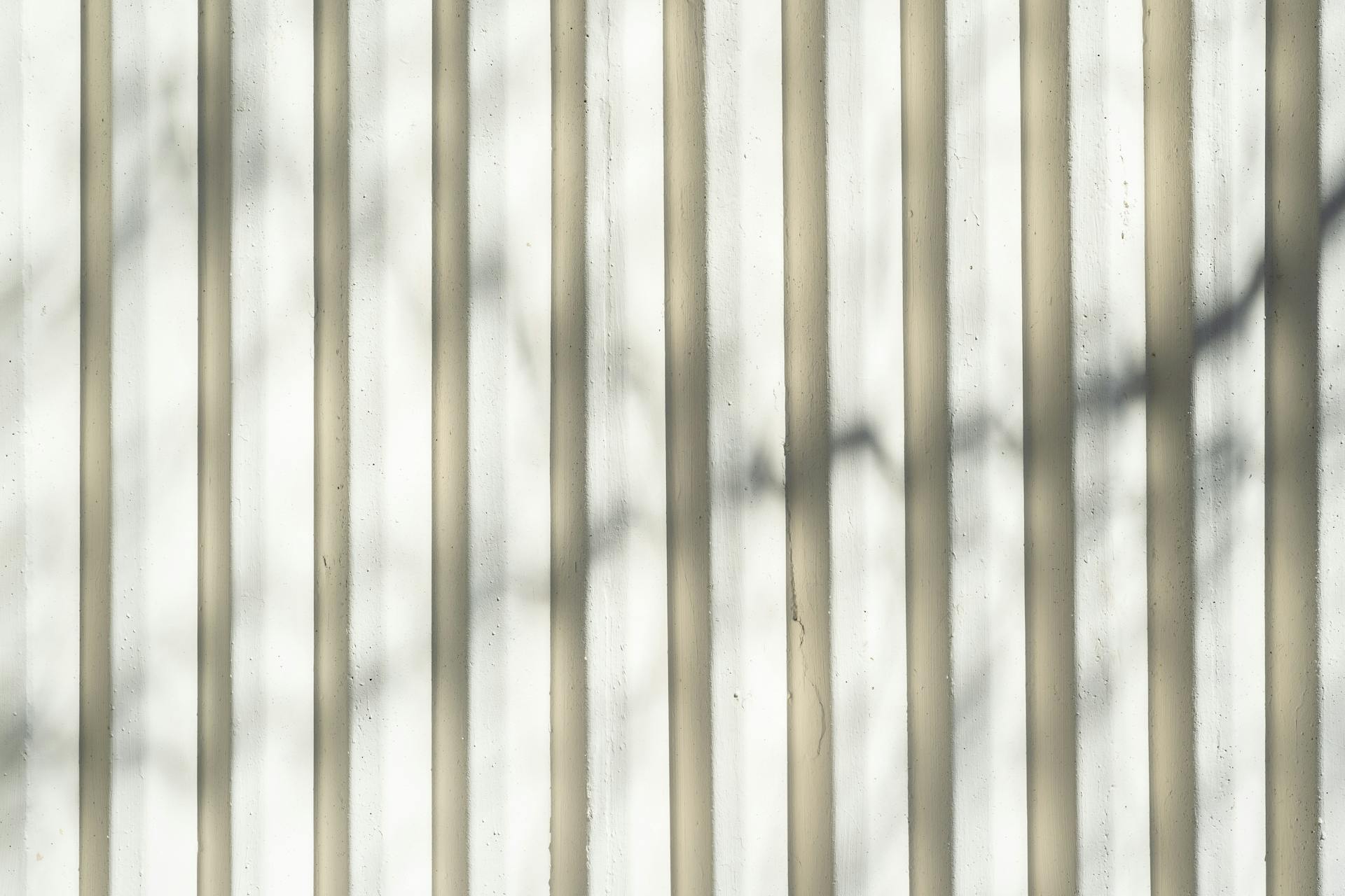 Abstract shadows on a corrugated white wall, creating a textured pattern.